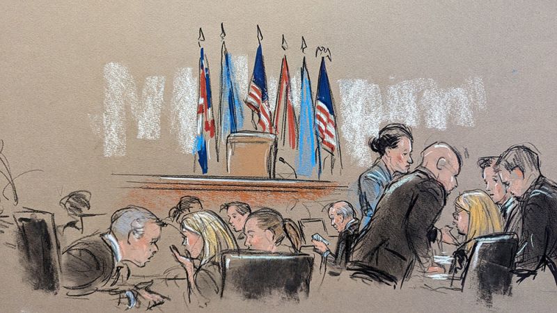 Lawyers for both sides talk amongst themselves. Lawyers for Dominion are seated on the left side of the room, with Fox's lawyers on the right. 